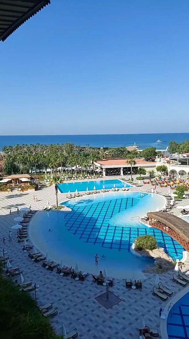Skats no augšas uz Selectum Family Resort Belek lagūnas tipa baseinu ar smilšu ieeju un tiltiņu pie jūras krasta.