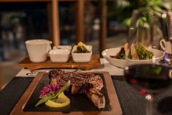 Papillon Zeugma Relaxury a la carte restorāna vakariņas ar grilētu steiku un vīnu — izsmalcināta servēšana uz koka dēļa vakara gaismā