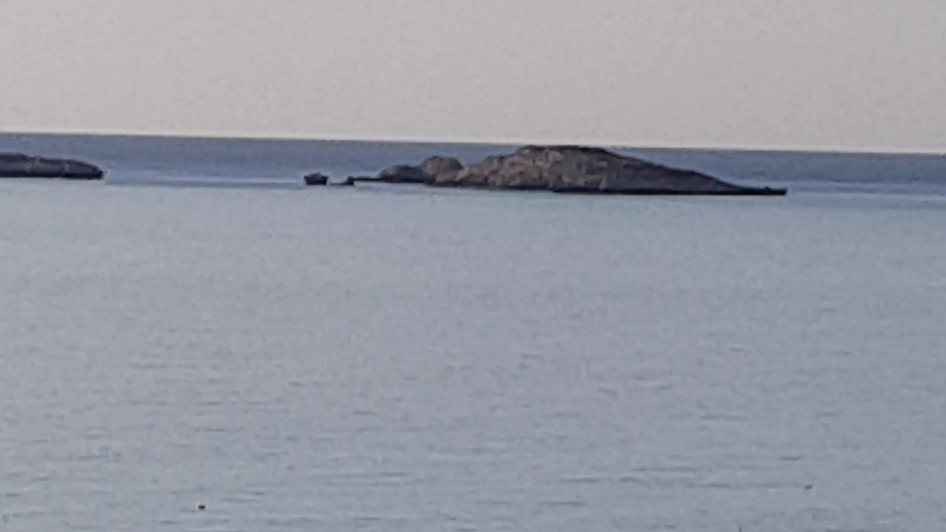 Skats uz nelielu akmeņainu salu jūrā netālu no Aquagrand Exclusive Deluxe Resort krasta Rodas salā Grieķijā