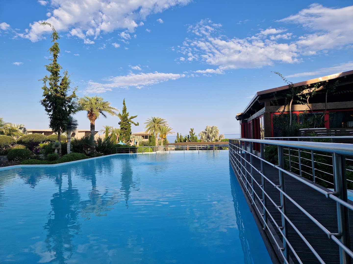 Aquagrand Exclusive Deluxe Resort bezgalības tipa baseins ar koka tiltiņu un apkārtējiem apstādījumiem zem skaidrām debesīm