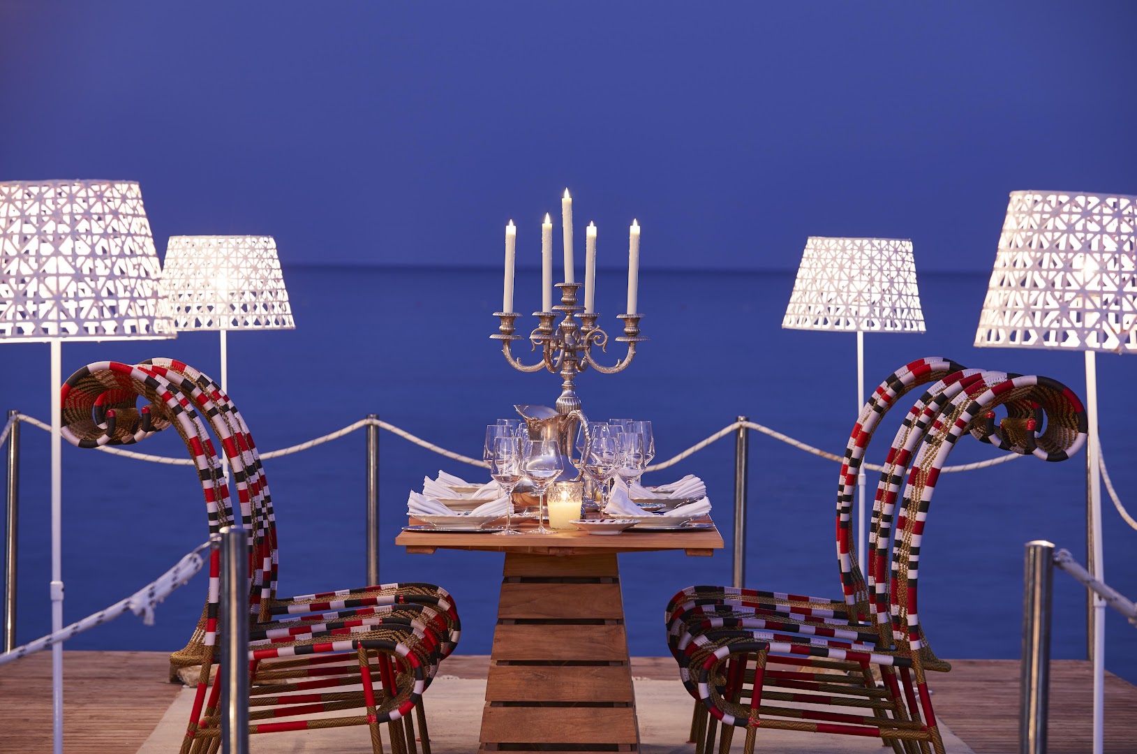 Eleganti klāts vakariņu galds uz koka platformas pie pašas jūras Aquagrand Exclusive Deluxe Resort viesnīcā Rodā vakarā