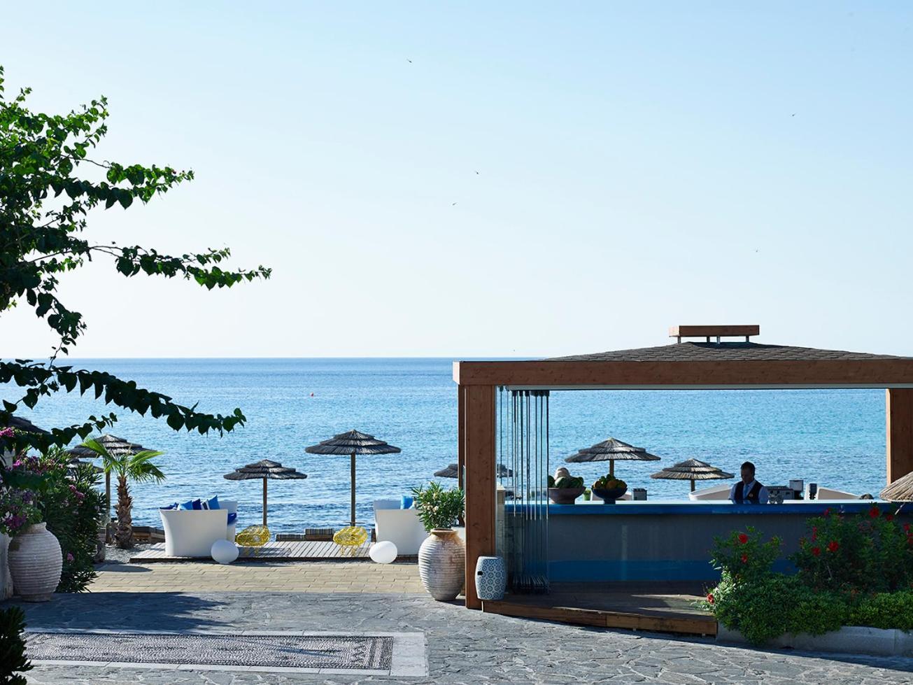 Aquagrand Exclusive Deluxe Resort pludmales bārs ar skatu uz jūru un saulessargiem Rodas salas piekrastē