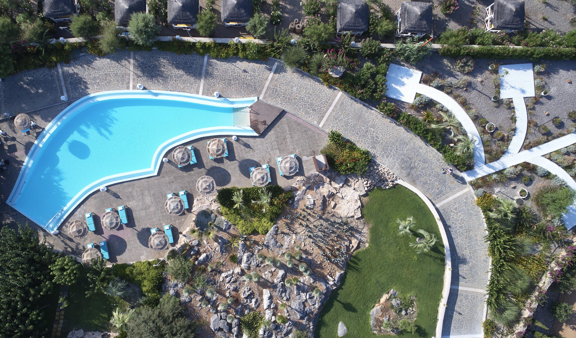 Aquagrand Exclusive Deluxe Resort teritorijas skats no augšas ar baseinu, dārza celiņiem, palmām un atpūtas nojumēm piekrastē