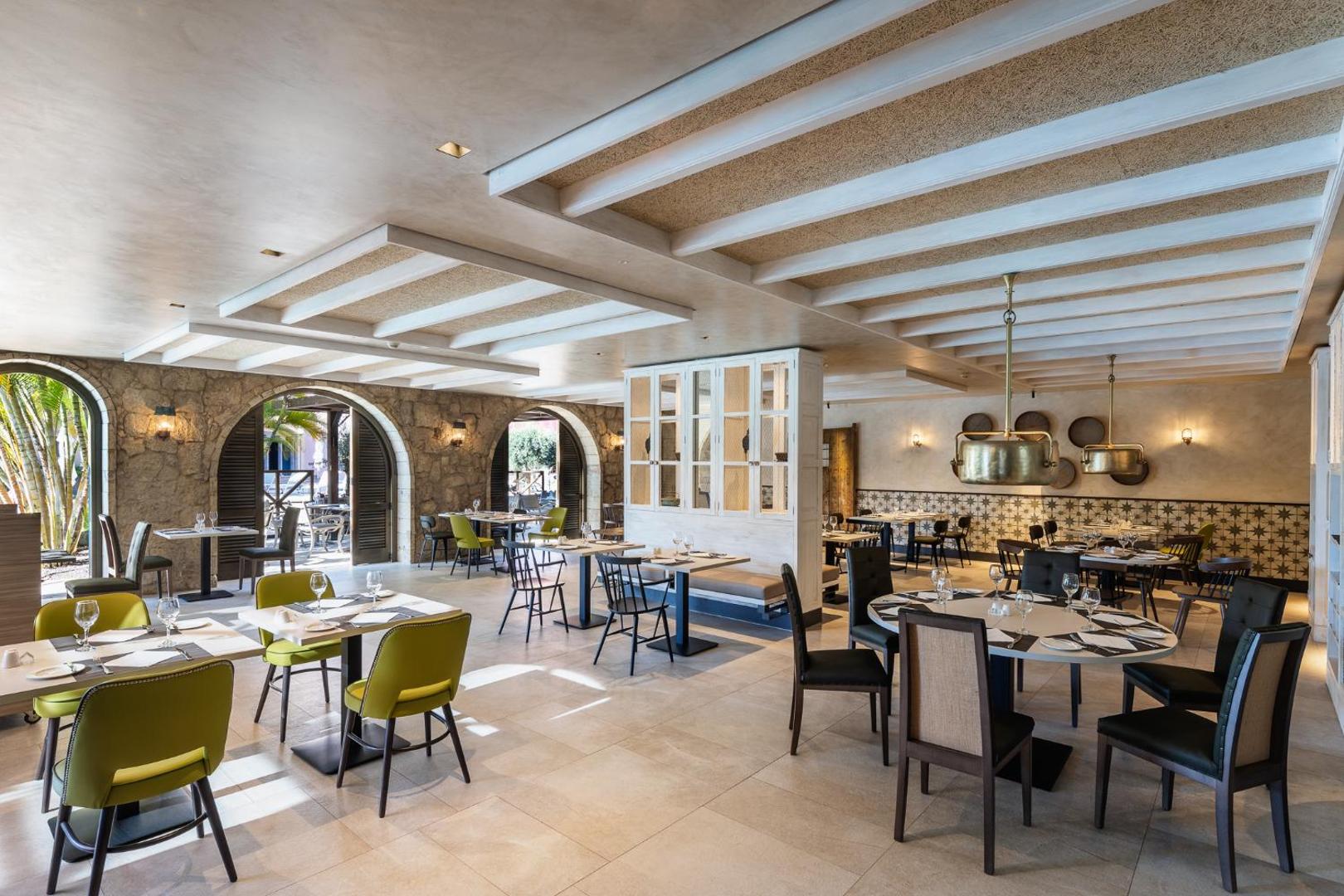 Lopesan Villa del Conde Resort & Thalasso elegants restorāns ar akmens arkām, modernām mēbelēm un gaišu interjeru vakariņām