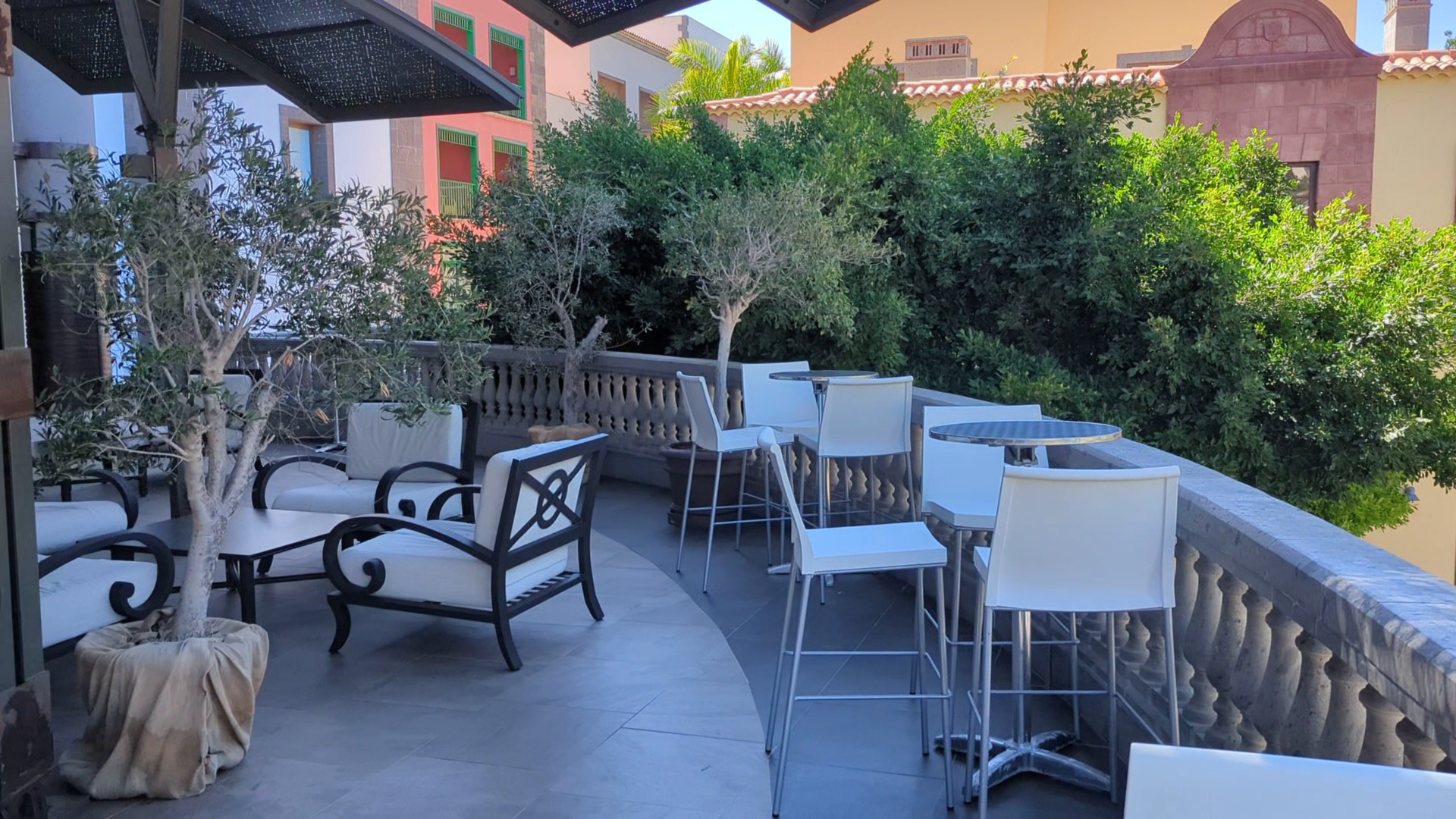 Lopesan Villa del Conde Resort & Thalasso āra terase ar modernām mēbelēm, olīvkokiem podos un skatu uz kūrorta arhitektūru Grankanārijā