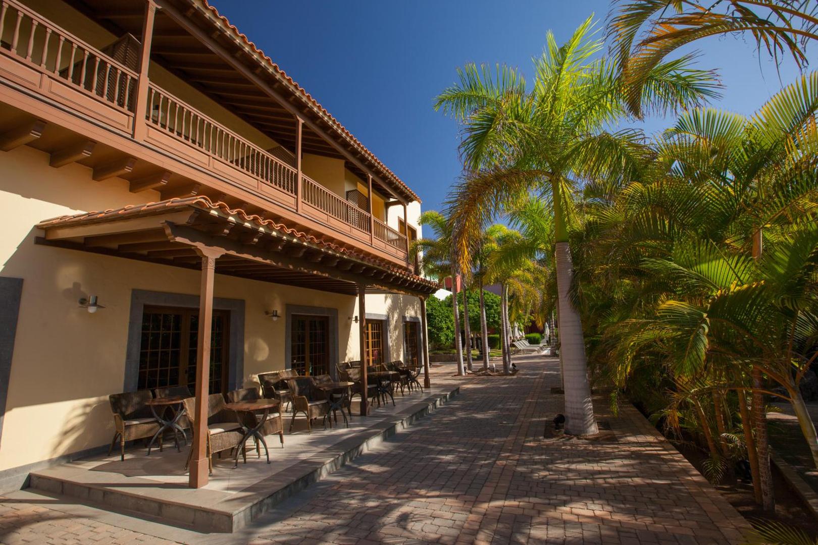 Lopesan Villa del Conde Resort & Thalasso tradicionālā stila terase ar koka balkoniem un pītiem krēsliem palmu ēnā