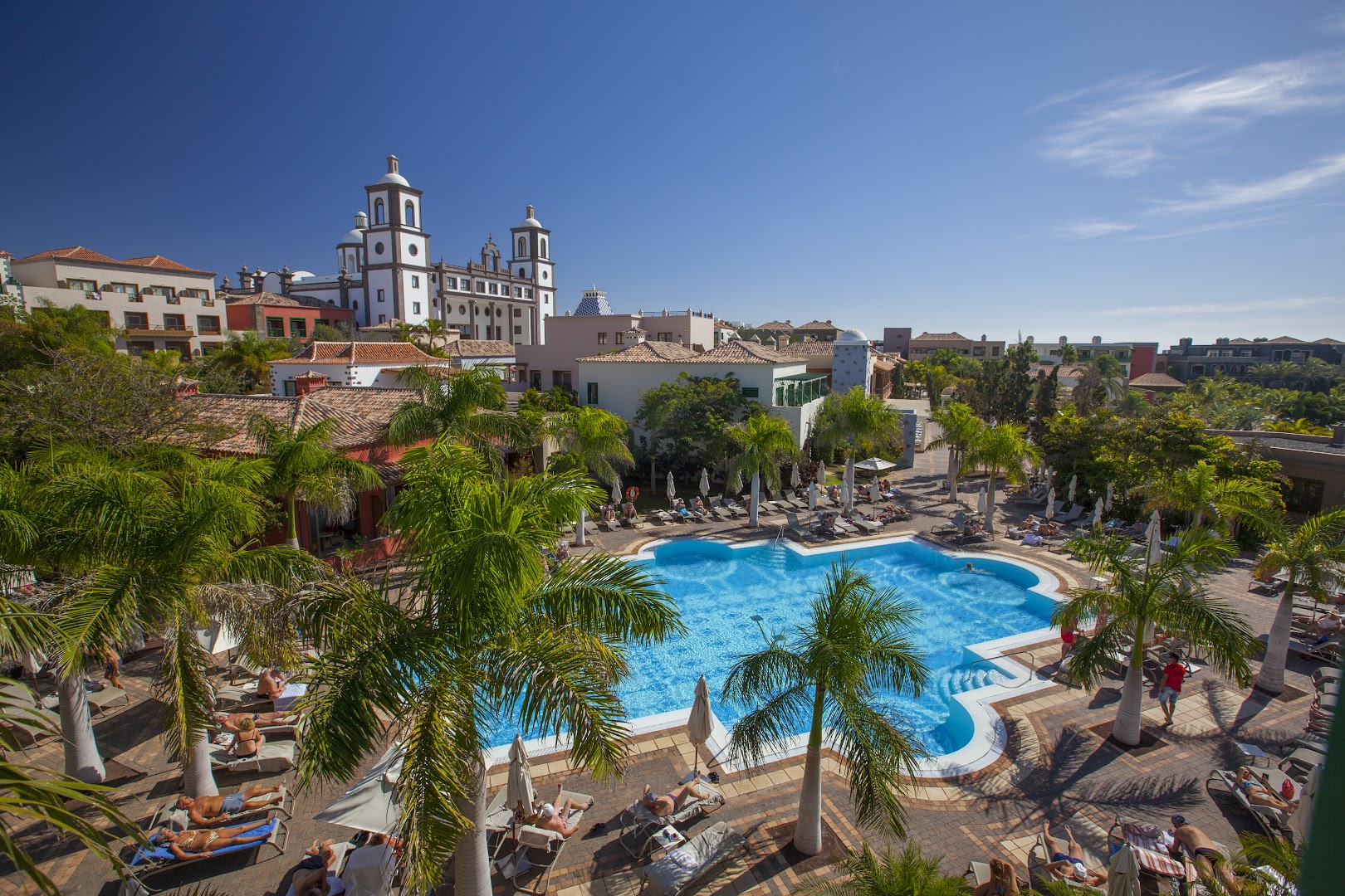 Lopesan Villa del Conde Resort & Thalasso centrālais baseins ar palmām un skatu uz viesnīcas katedrāles stila ēku Grankanārijā
