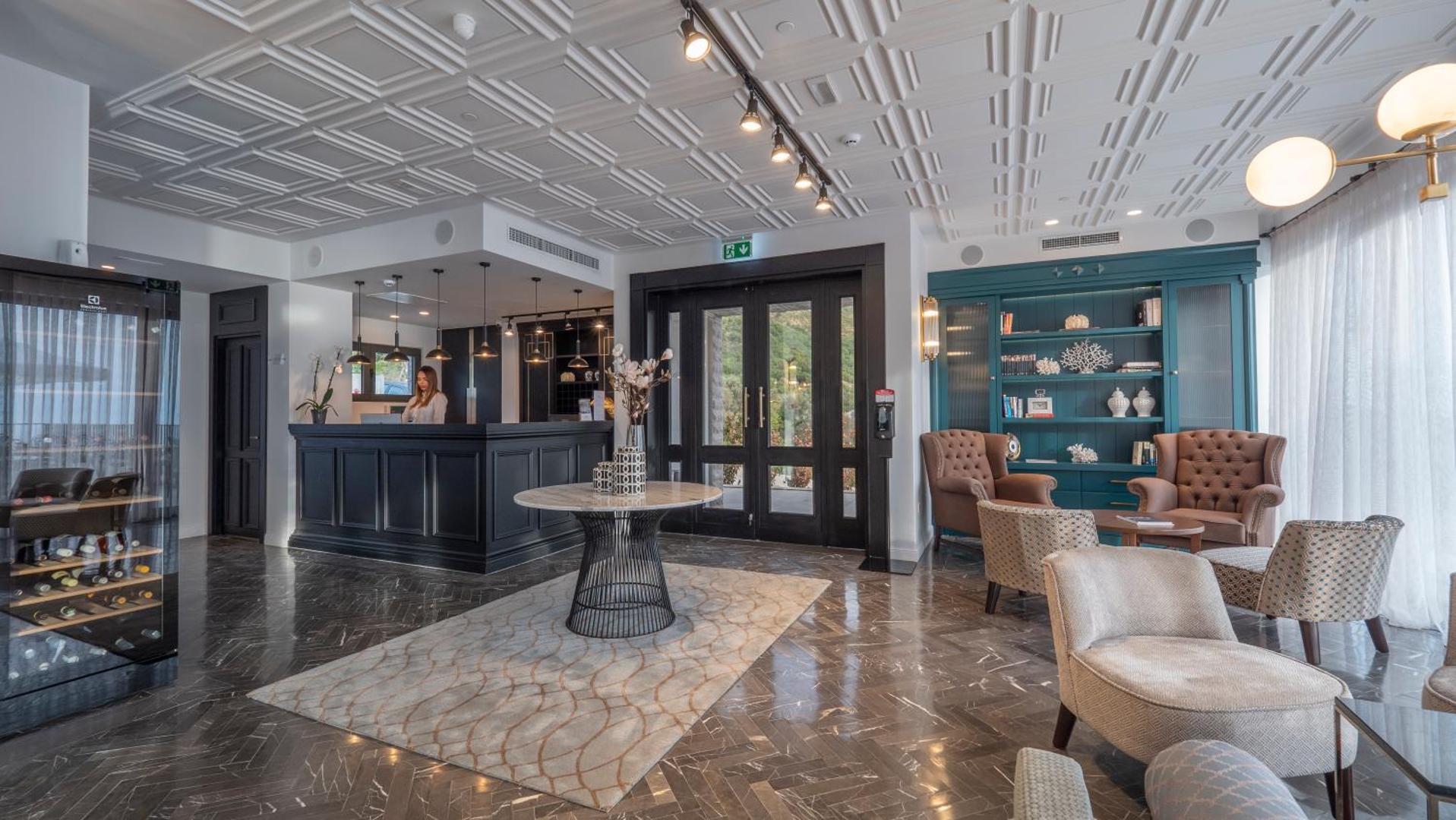 Vivid Blue Serenity Hotel vestibils un lobby zona ar tumšu recepcijas leti, marmora grīdu un stilīgiem atpūtas krēsliem
