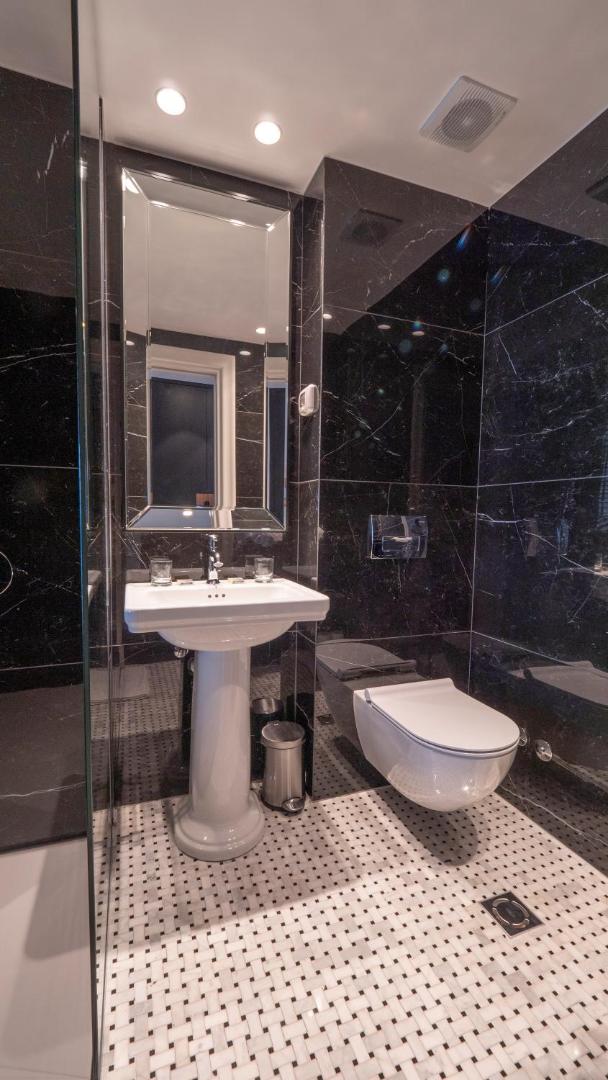 Vivid Blue Serenity Hotel moderna vannas istaba ar melna marmora sienām, klasisku izlietni un melnbaltu mozaīkas flīžu grīdu