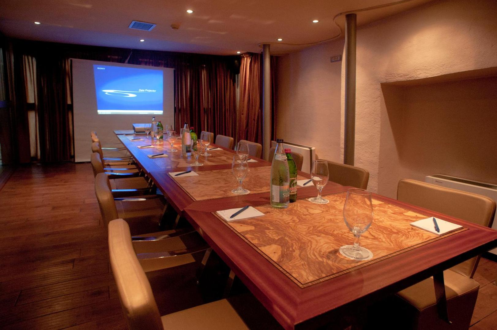 Astoria Boutique Hotel konferenču zāle ar garu koka galdu, krēsliem un projektora ekrānu prezentācijām Budvā, Melnkalnē