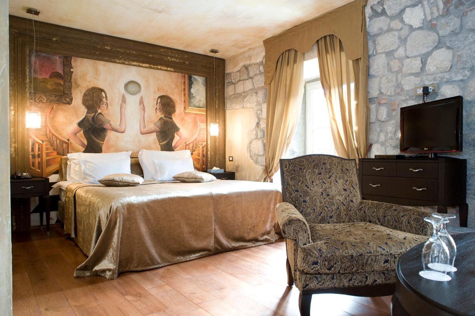 Astoria Boutique Hotel numura interjers ar greznu sienas gleznojumu, klasisku atpūtas krēslu un dabīgā akmens sienas elementiem