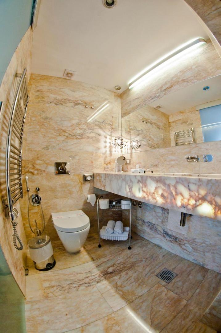 Astoria Boutique Hotel vannas numurs ar marmora apdari, lielu spoguli un modernu santehniku gaišos toņos