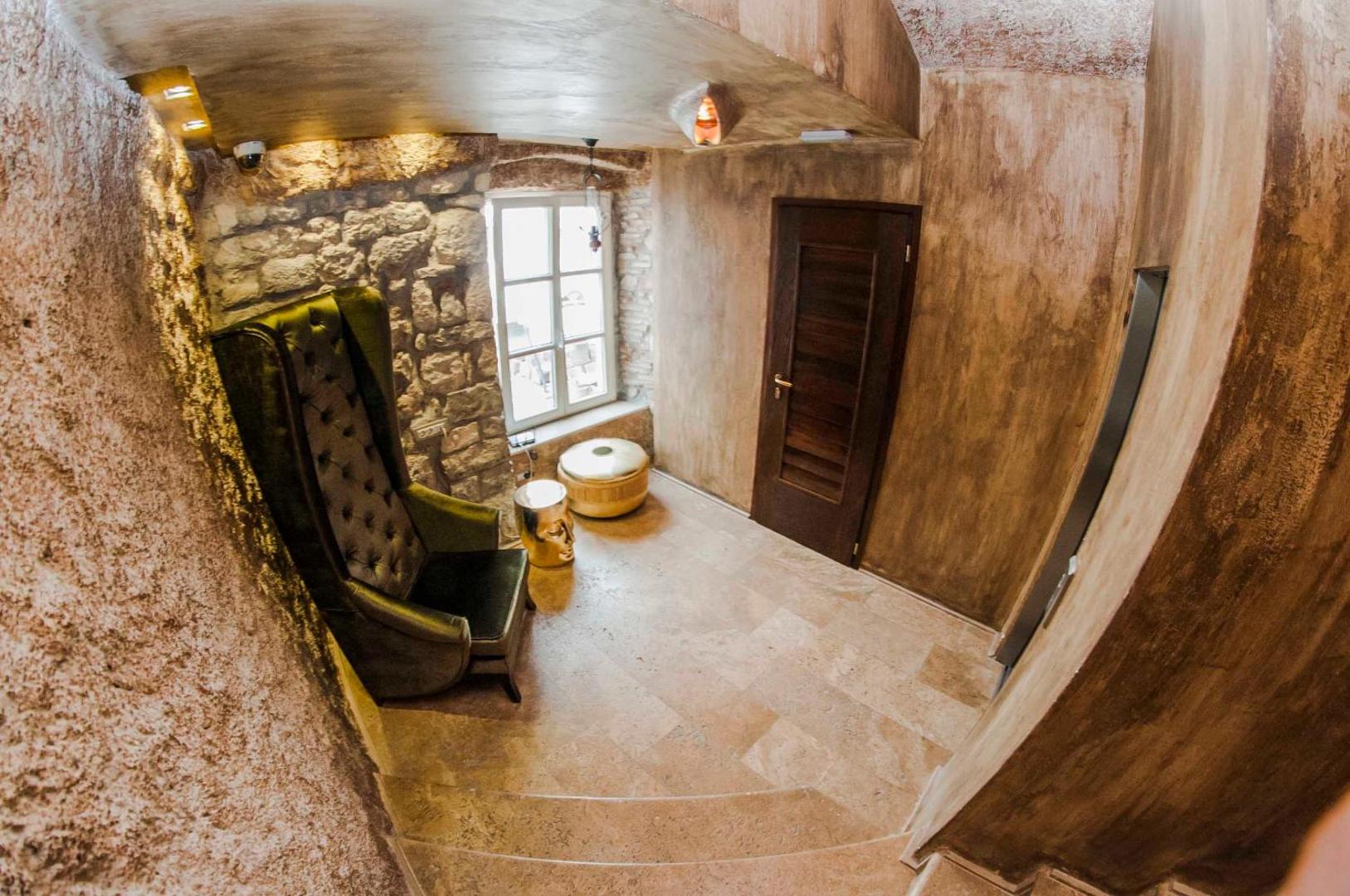 Astoria Boutique Hotel atpūtas stūrītis ar zaļu samta krēslu, akmens sienu un dekoratīviem elementiem vēsturiskā stilā