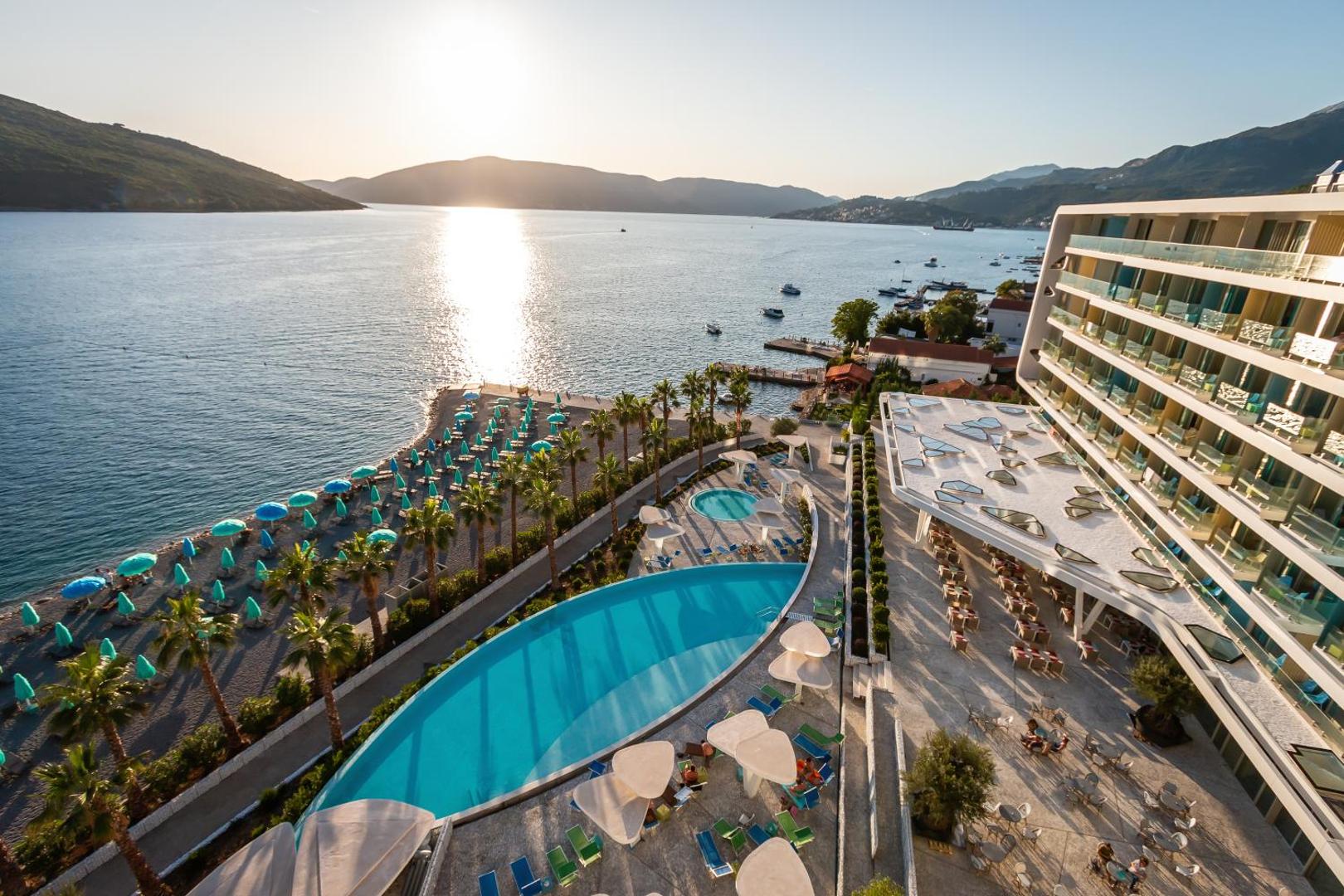Carine Hotel Kumbor Superior skats no augšas uz āra baseiniem, privāto pludmali un Adrijas jūras līci saulrietā Melnkalnē