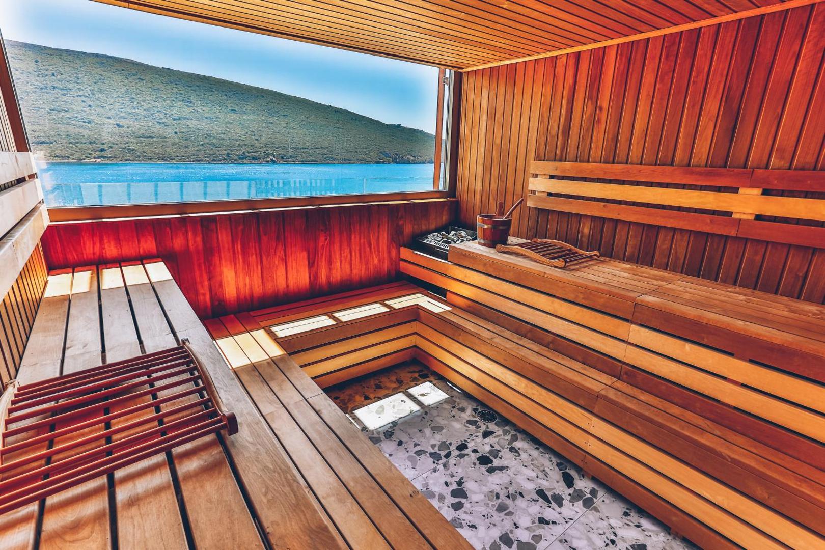 Carine Hotel Kumbor Superior spa centra sauna ar lielu panorāmas logu, no kura paveras skats uz kalniem un jūras līci.