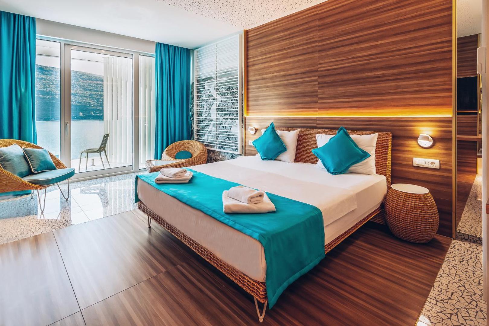 Carine Hotel Kumbor moderns numurs ar divguļamo gultu, koka sienu paneļiem un skatu uz jūru Melnkalnē — gaišs interjers ar tirkīza akcentiem