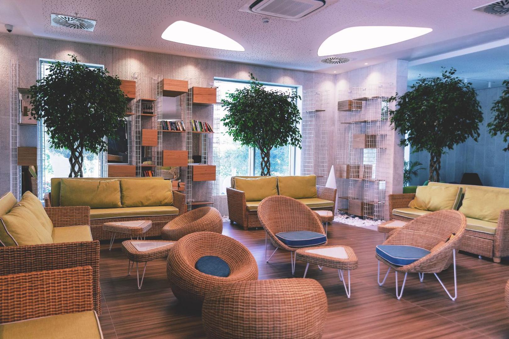 Carine Hotel Kumbor Superior lobby atpūtas zona ar pītiem krēsliem, zaļiem augiem un mājīgiem dīvāniem relaksācijai iekštelpās.