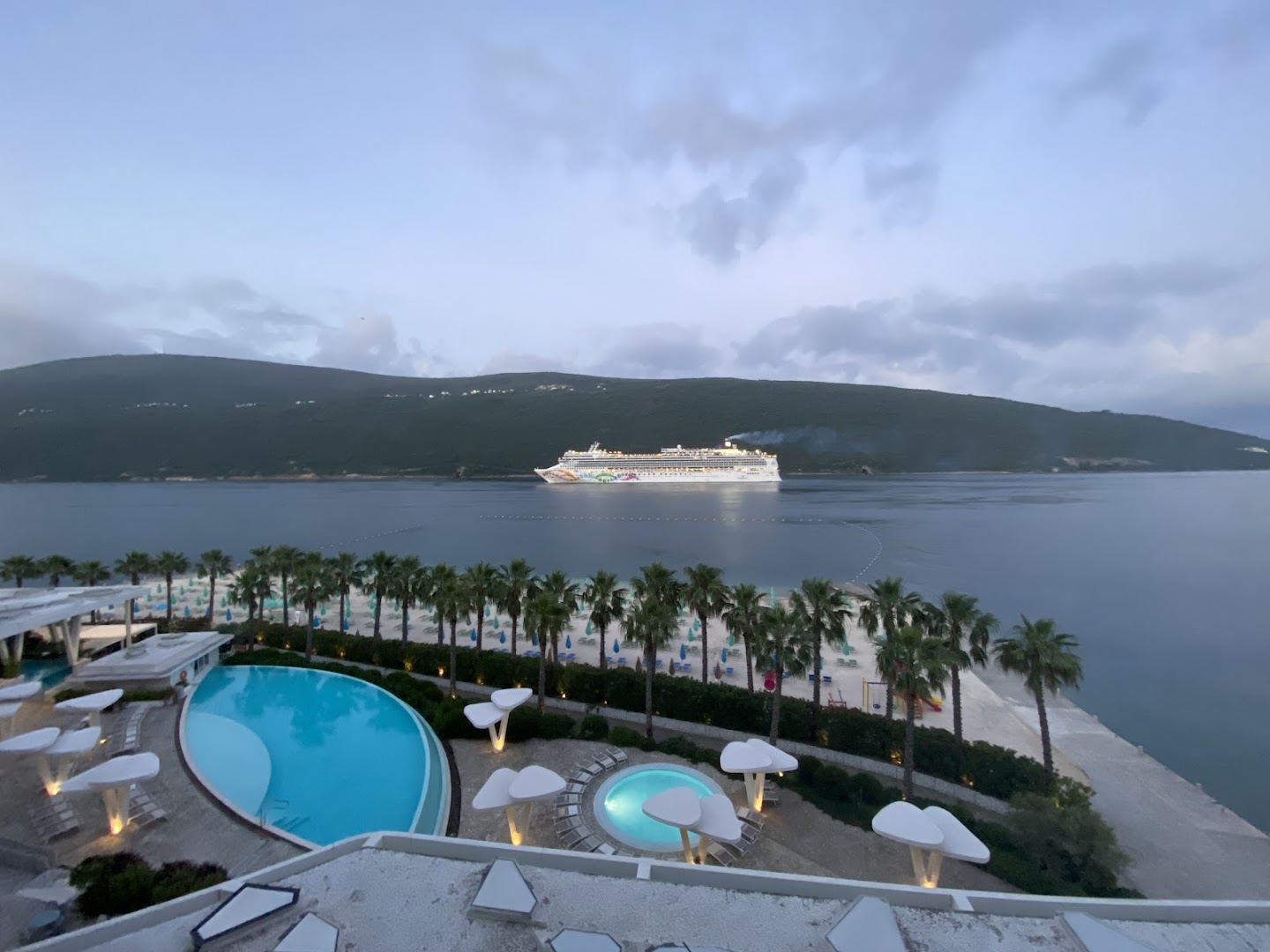 Vakara skats no Carine Hotel Kumbor Superior uz izgaismotiem baseiniem, pludmali un kruīza kuģi Kotoras līcī