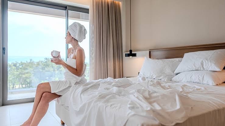 Viesis bauda rīta kafiju Iolida Corfu Resort & Spa numurā pie liela loga ar skatu uz jūru