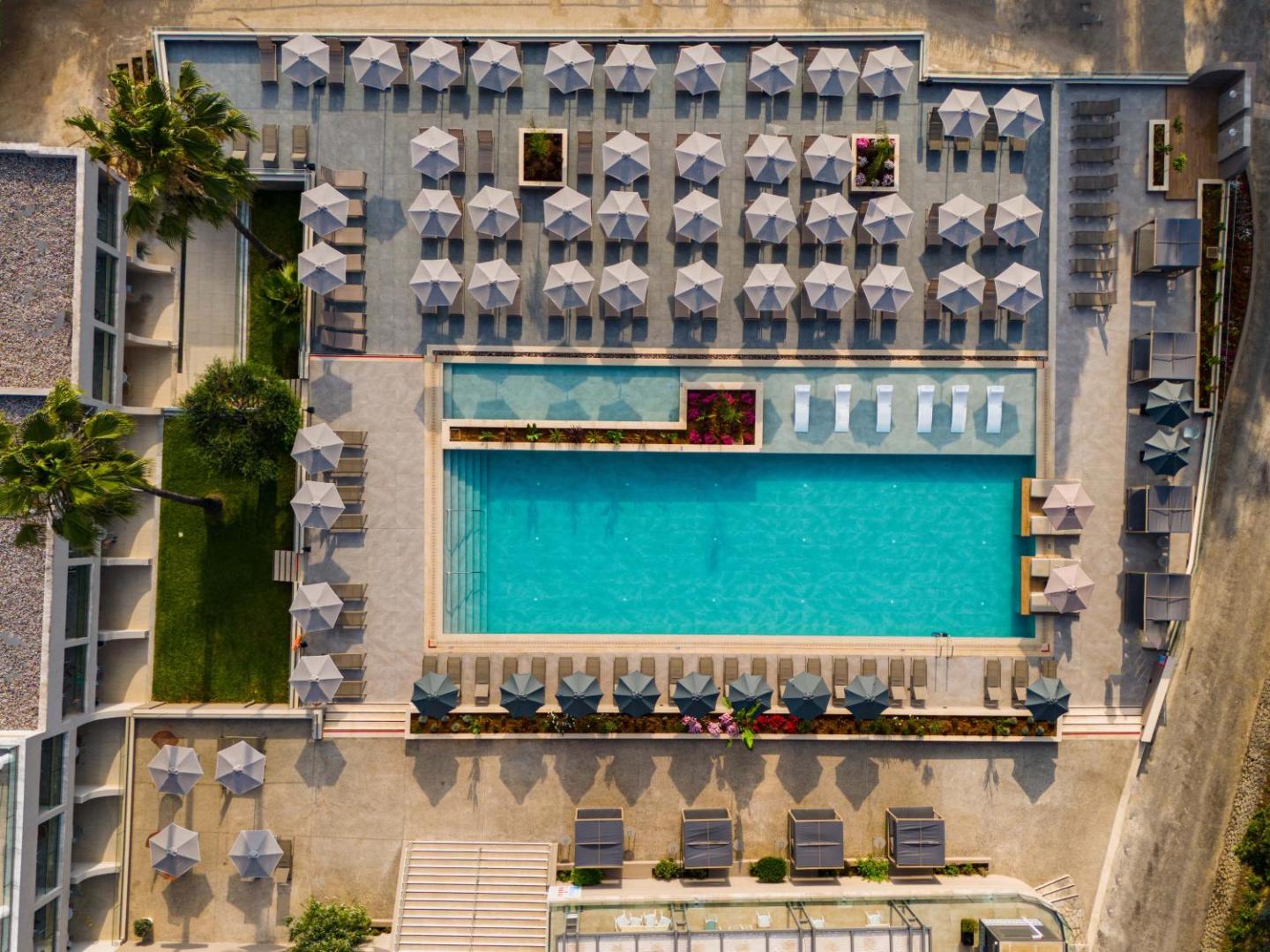 Iolida Corfu Resort & Spa galvenā baseina teritorija Dassia, Korfu — skats no augšas uz sauļošanās terasi un palmu dārzu