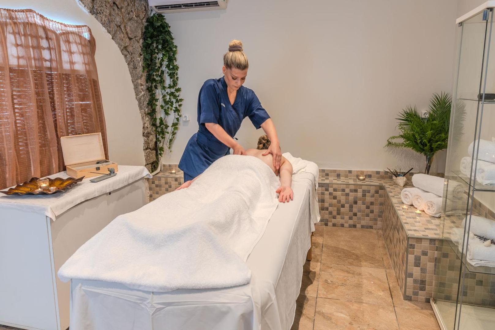 Iolida Corfu Resort & Spa spa centrs ar masāžas galdu un profesionālu terapeitu procedūras laikā
