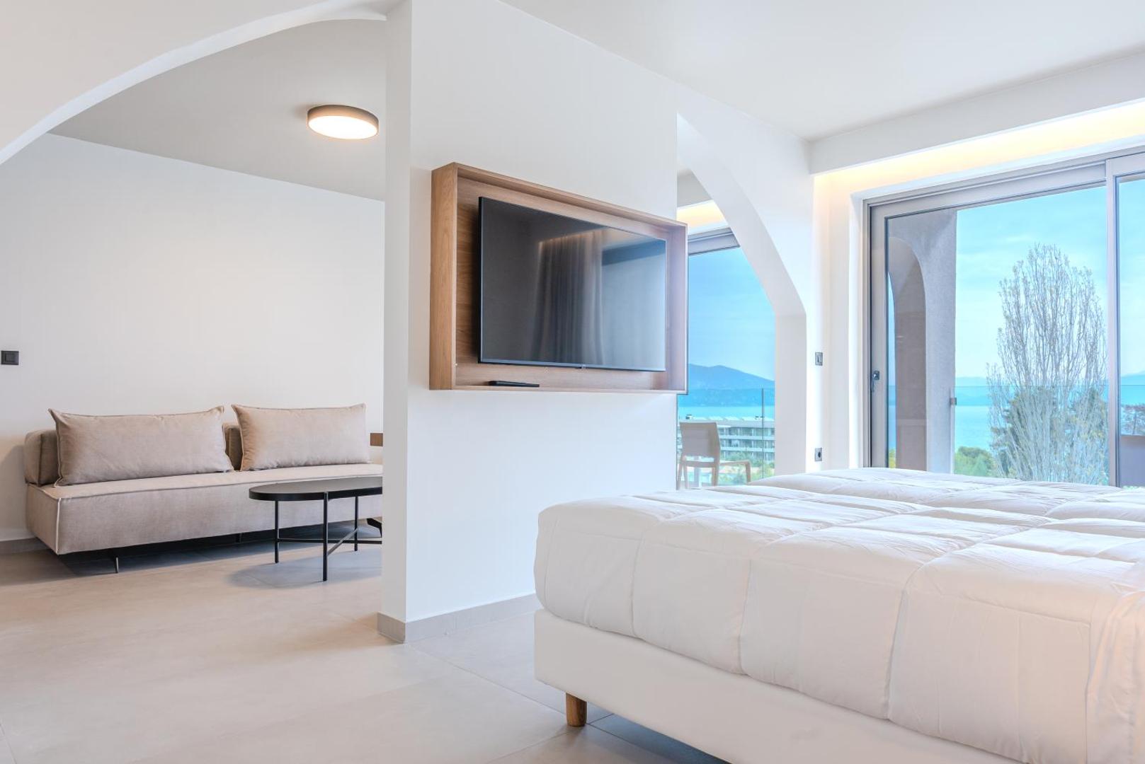 Iolida Corfu Resort & Spa gaišs numurs ar atpūtas zonu, dīvānu un skatu uz Jonijas jūru Korfu salā