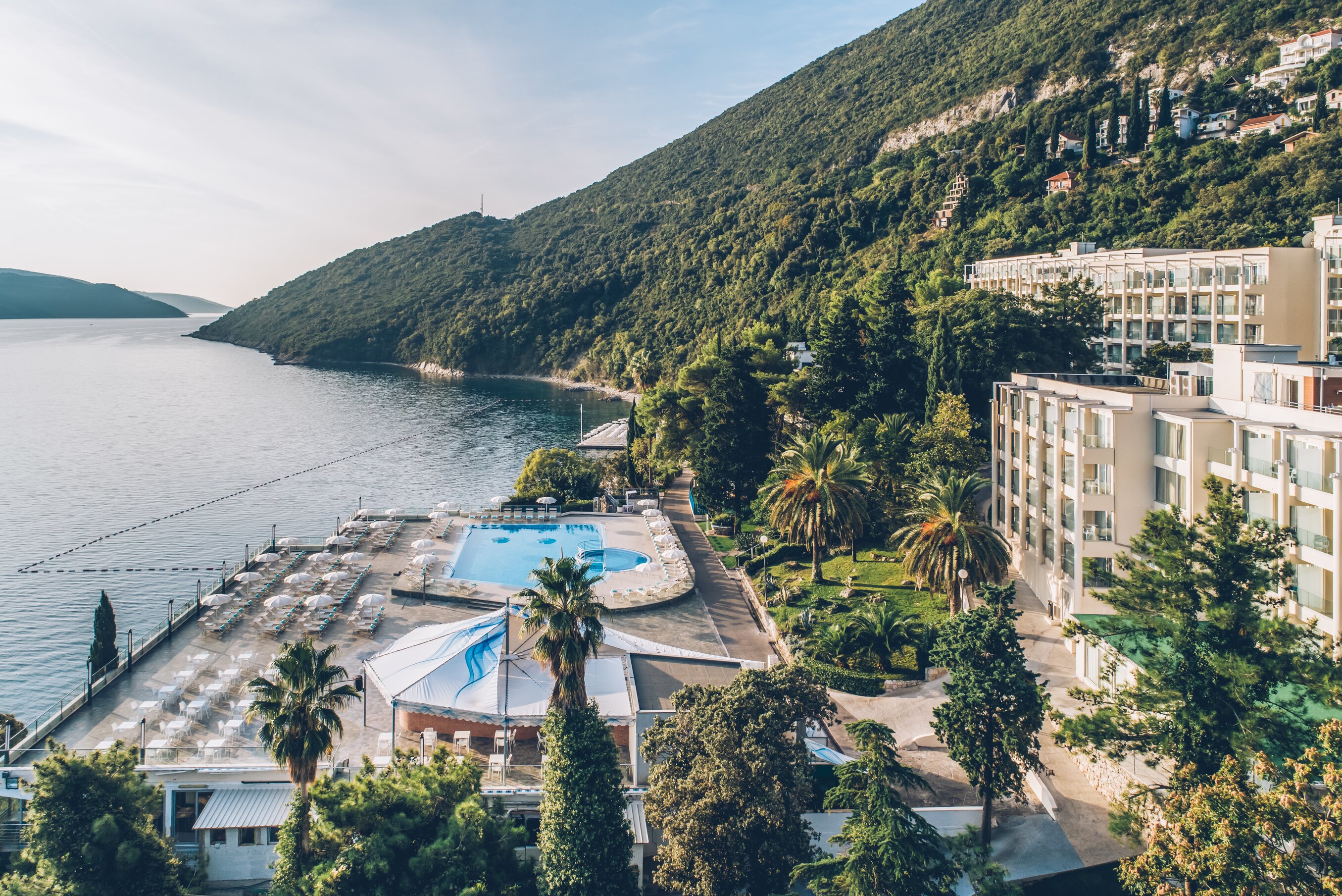 Viesnīca pie jūras ar baseinu un apkārtējiem palmu kokiem, apskatot kalnu ainavas. Ideāla vieta atpūtai un relaksācijai. panoramic view with beach and pools