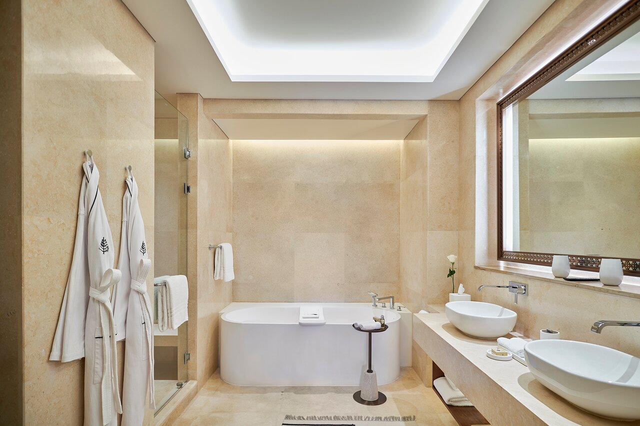 Four Seasons Resort Sharm El Sheikh eleganta vannas istaba ar marmora apdari un brīvstāvošu vannu.