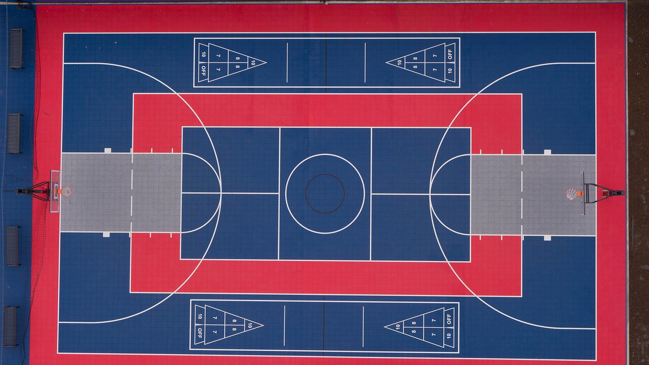 Basketbola laukums ar sarkanu un zilu dizainu.