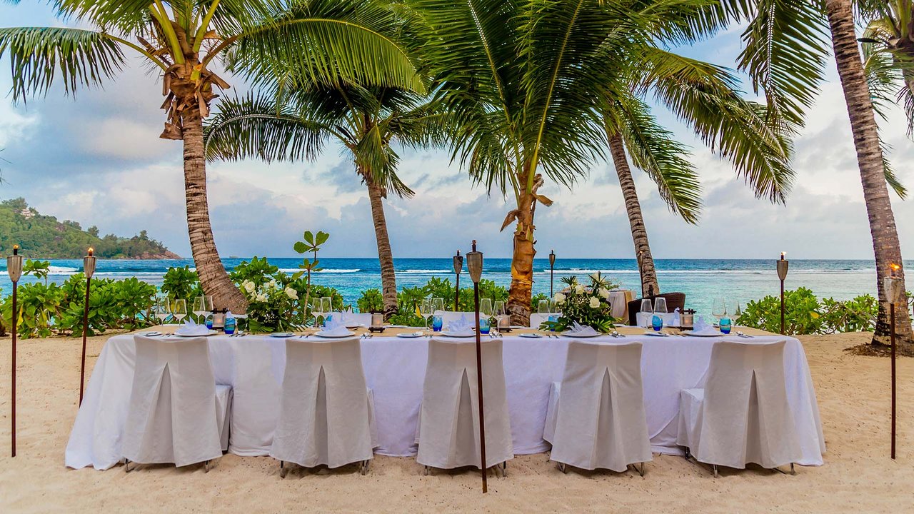 Kempinski Seychelles Resort klāts galds pludmalē ar skatu uz okeānu