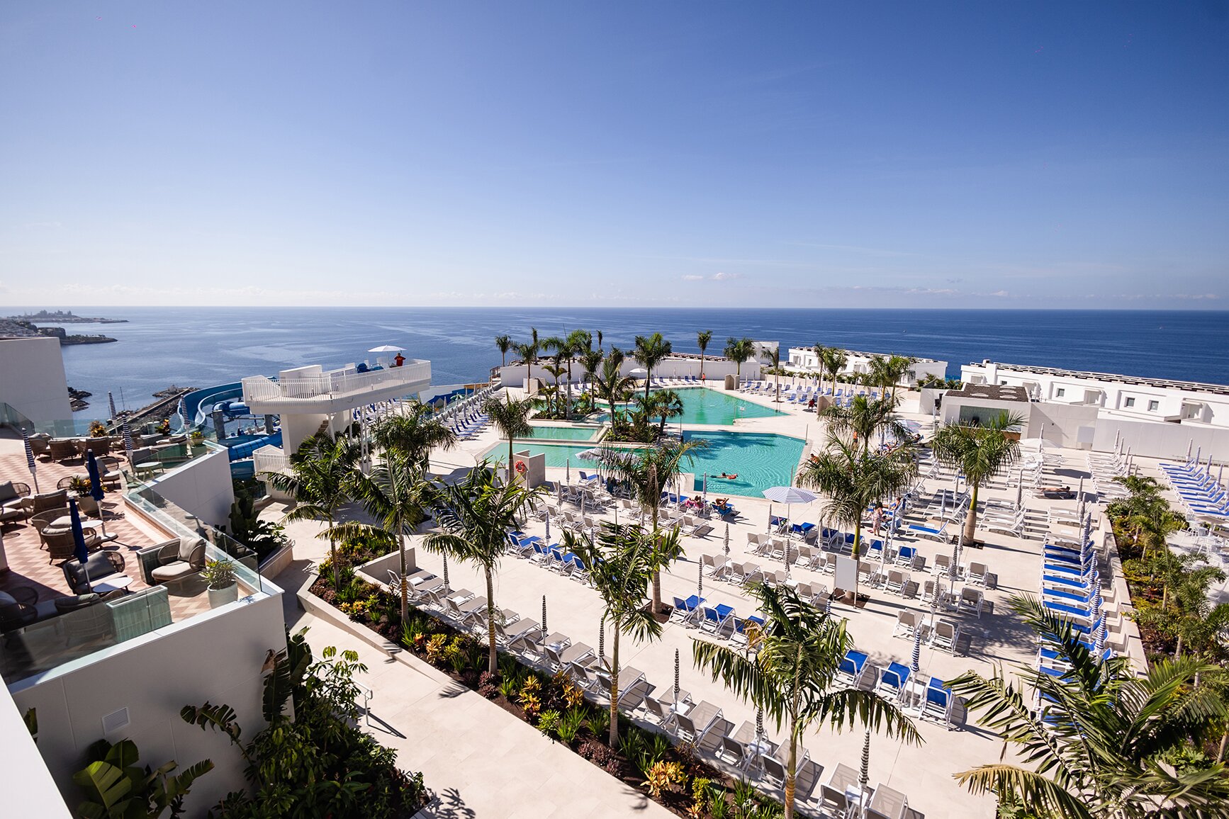 Moderns kūrorts ar baseinu un skatu uz jūru, kurā ir saulainas terases un sauļošanās krēsli. Ideāla vieta atpūtai un atpūtas brīžiem. panoramic view with beach and pools