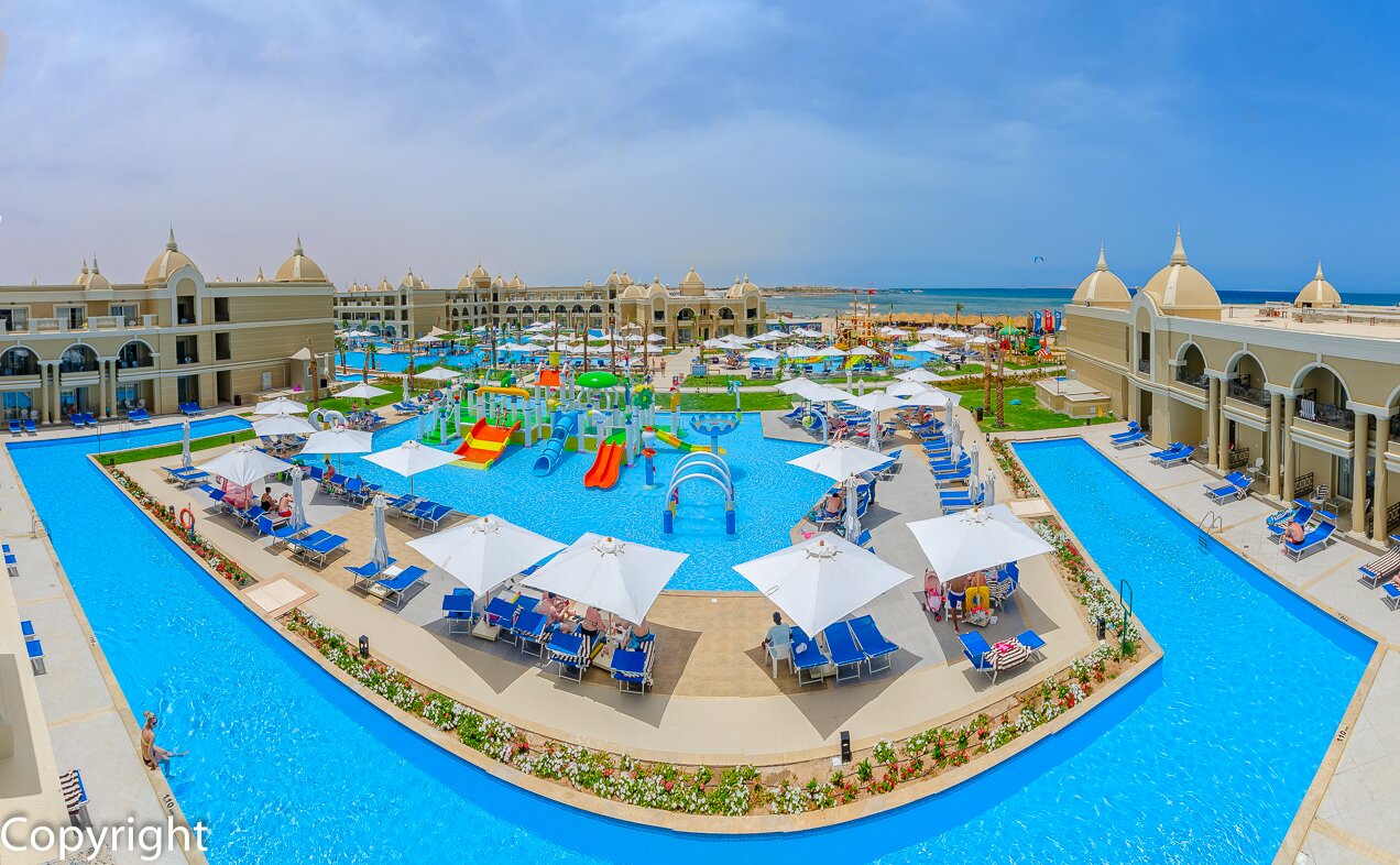 Lielisks kūrorts ar plašu baseinu un ūdens atrakciju parku, kas atrodas blakus jūrai. Viesi atpūšas zem saules, baudot vasaras priekus. panoramic view with beach and pools