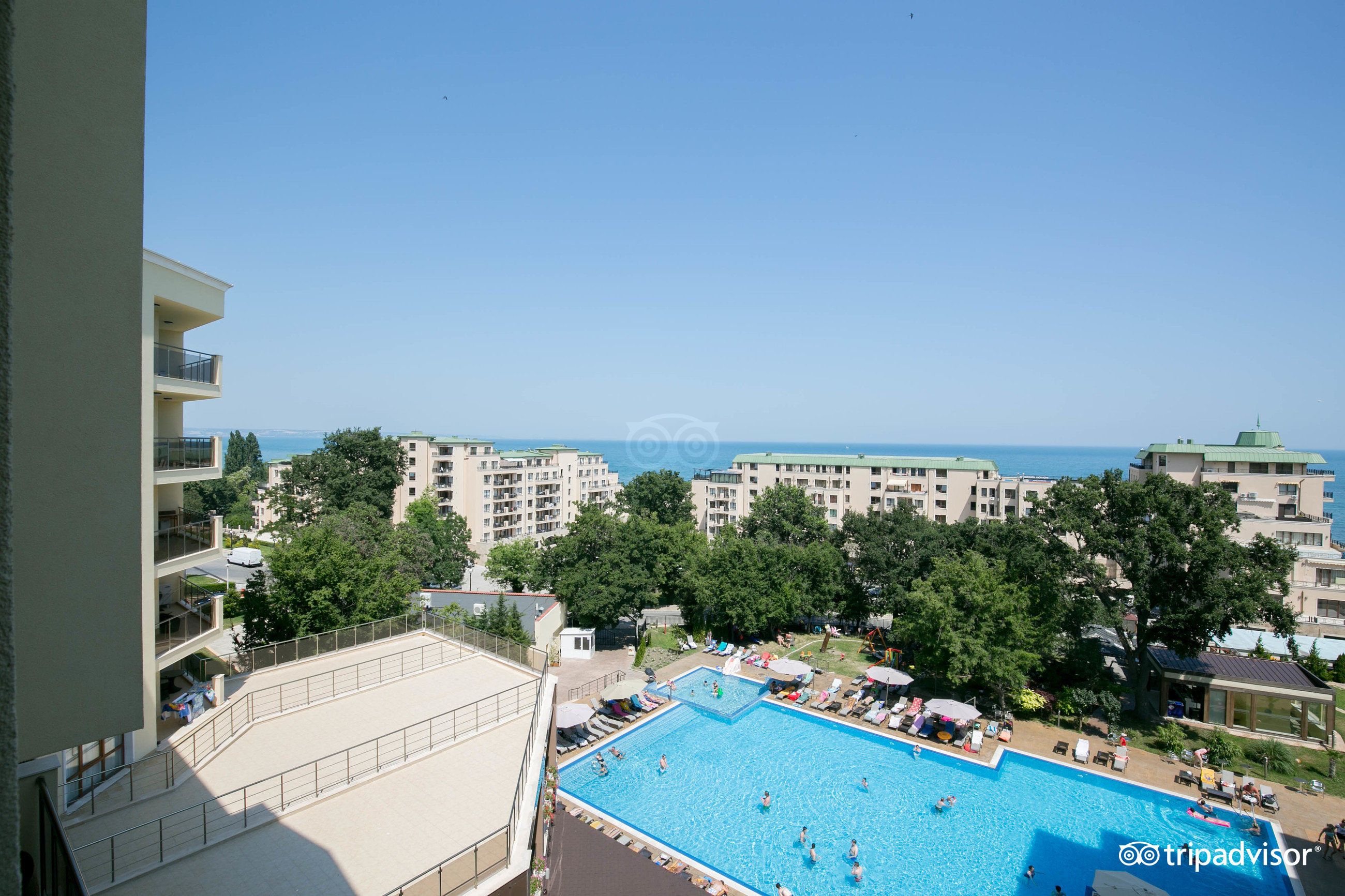 Skats uz viesnīcu kompleksu ar baseinu un tuvumā esošām ēkām, kā arī jūras skatu un skaidru debesi. panoramic view with beach and pools