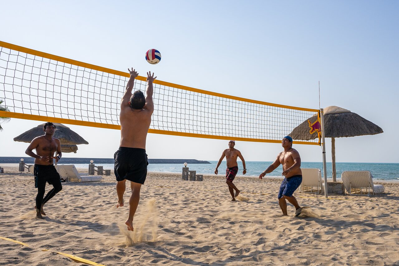 Viesi spēlē pludmales volejbolu The Cove Rotana Resort piekrastē.